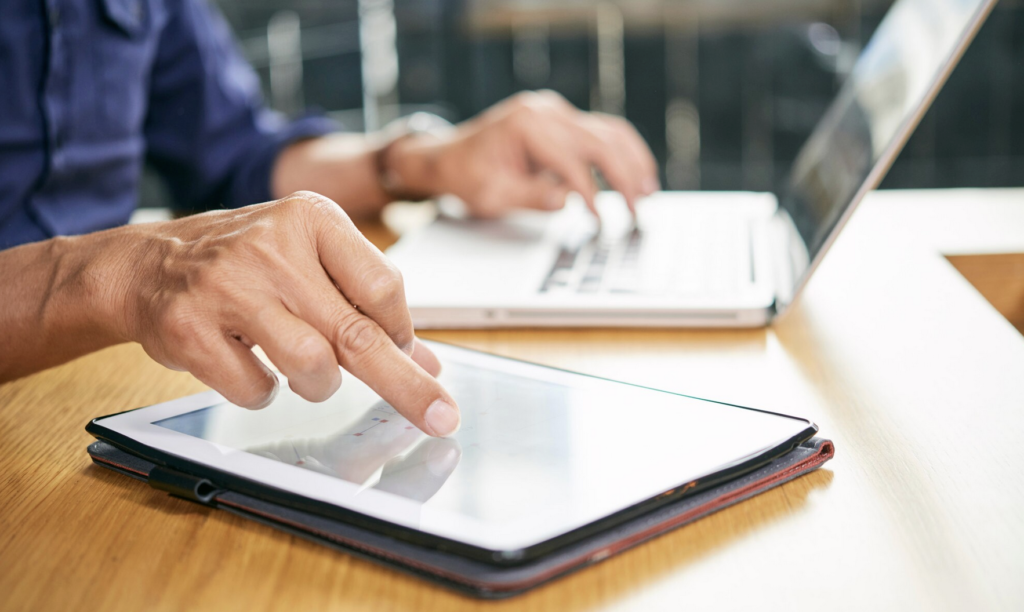 someone filling out electronic forms on laptop and tablet